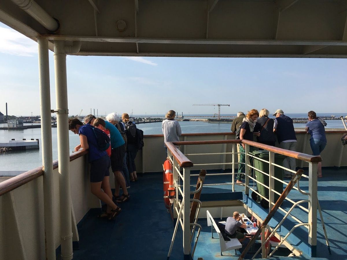 Passagiers aan de reling op het buitendek van een veerboot